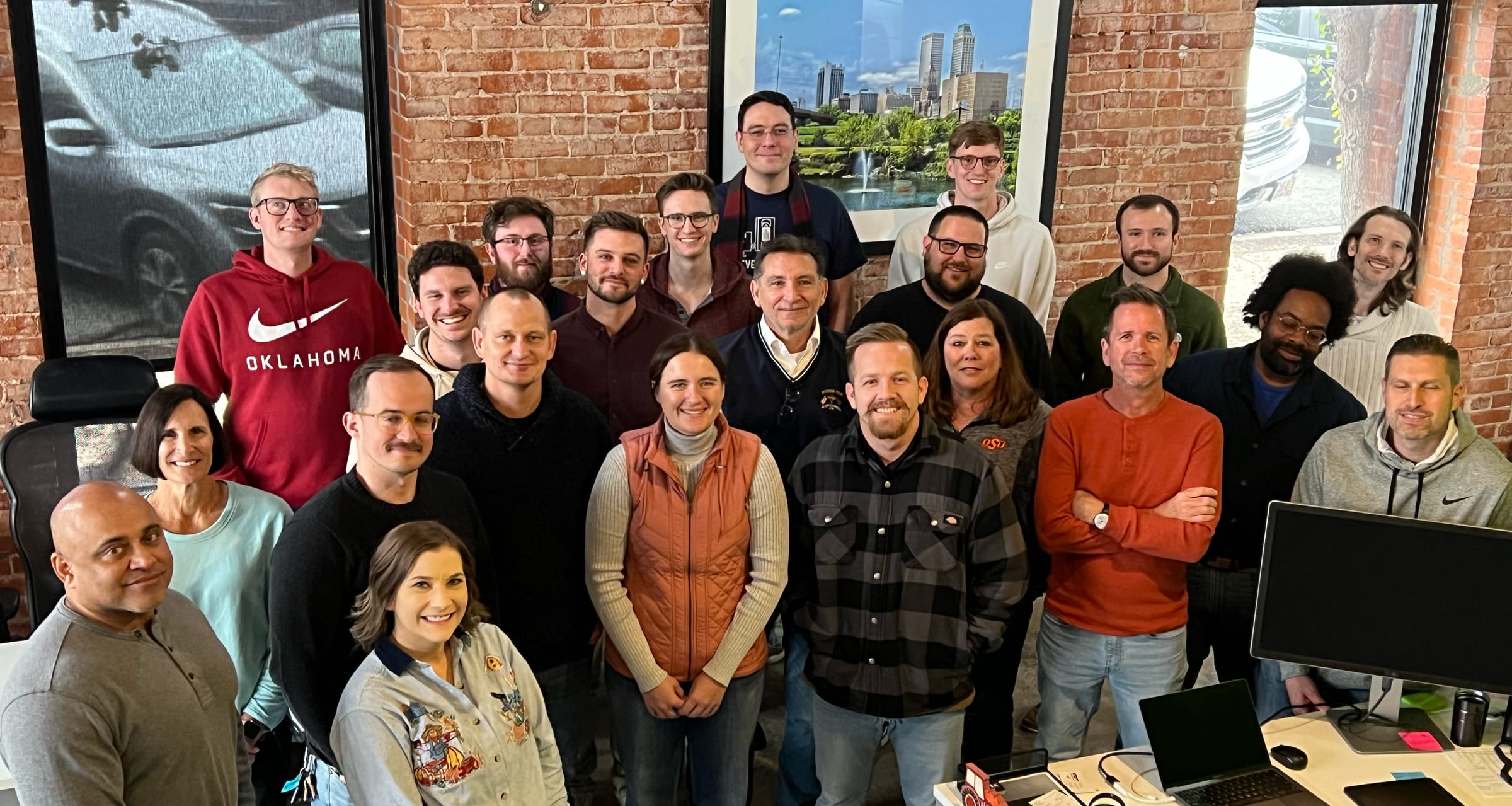 The SEQTEK team at the downtown Tulsa office, with the Tulsa skyline on the wall